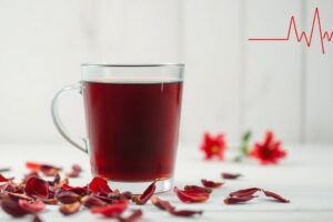 🌺 Hibiscus Tea and Blood Pressure: A Delicious Way to Support Heart Health A steaming glass cup of red hibiscus tea surrounded by dried petals, symbolizing its natural role in supporting healthy blood pressure.