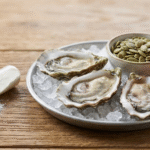 Zinc supplement capsule and zinc-rich foods like oysters and pumpkin seeds on a table, representing sources of zinc for prostate health.